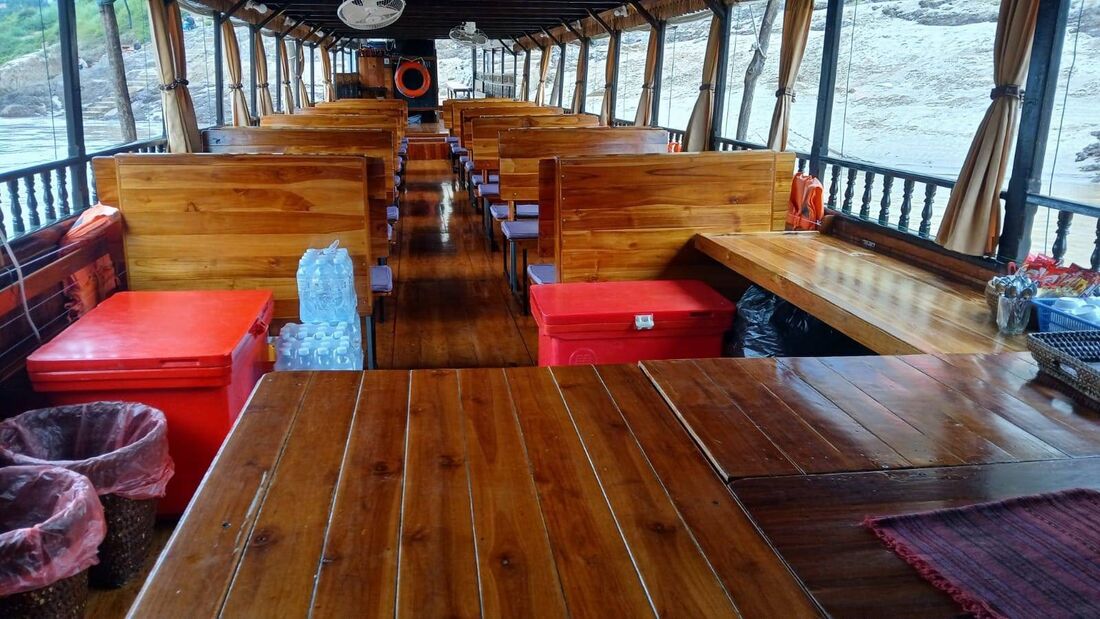 Inside the covered slow boat with wooden benches and open river views